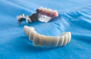 A front shot of a set of dentures resting ion a blue clloth