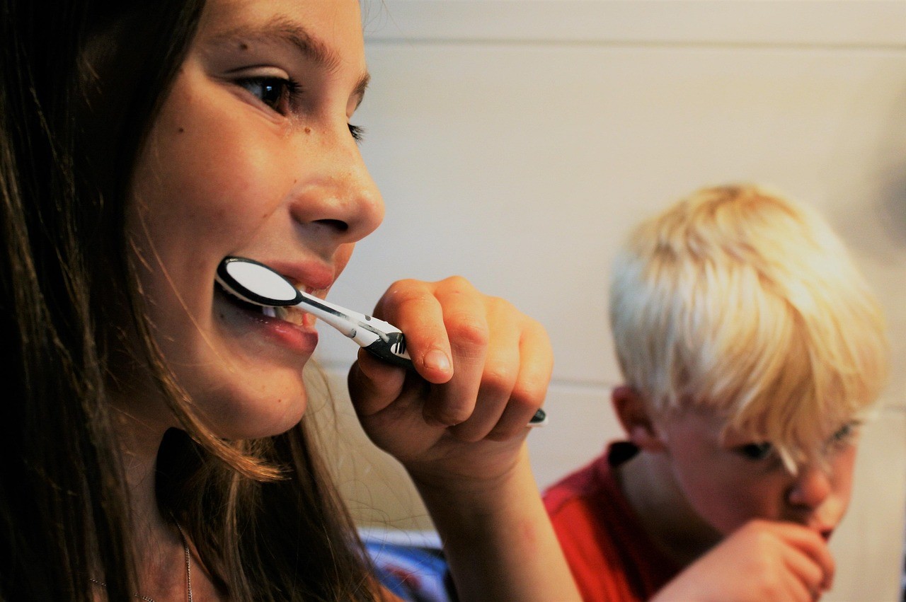 Young girl and boy siblings brushing their teeth together